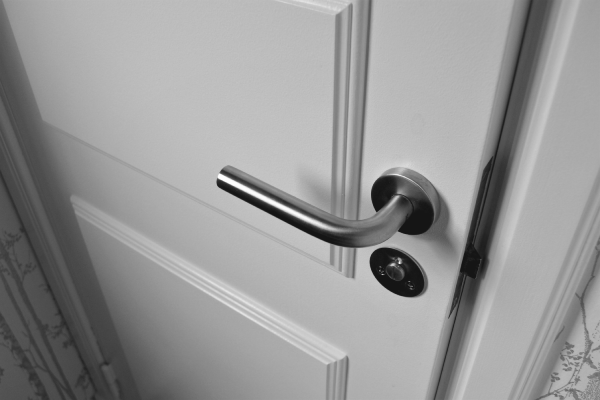Close-up photo of semi-open white door with polished gray handle.