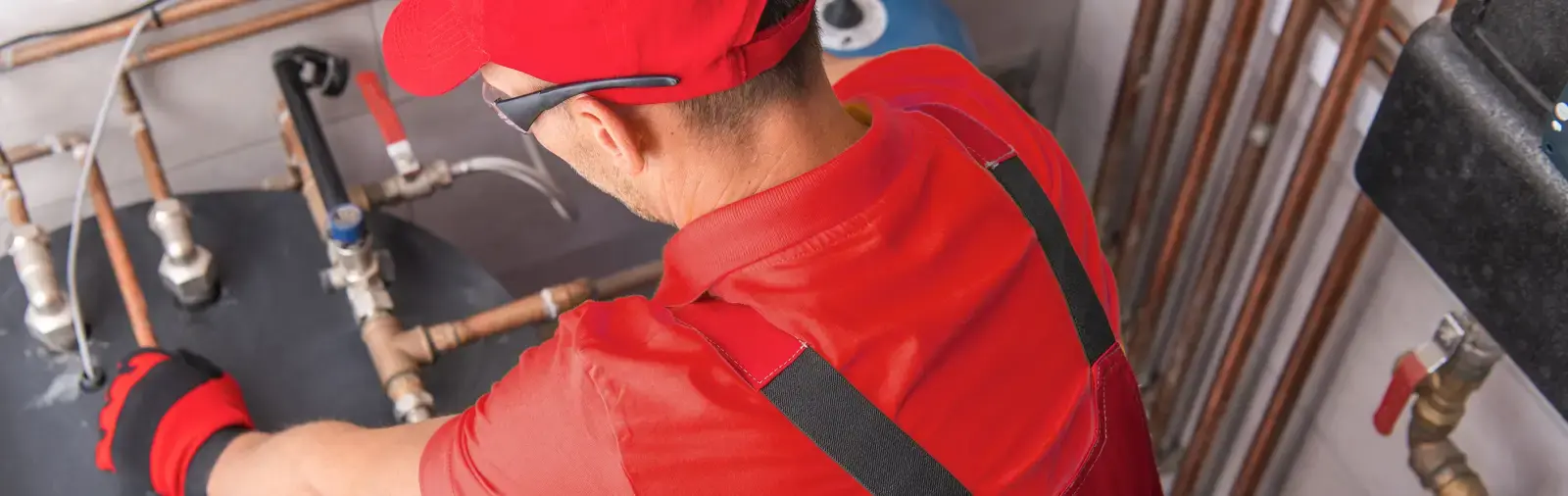 A service professional works on pipes connected to a water heater system
