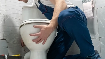 Worker adjusting toilet to its base.