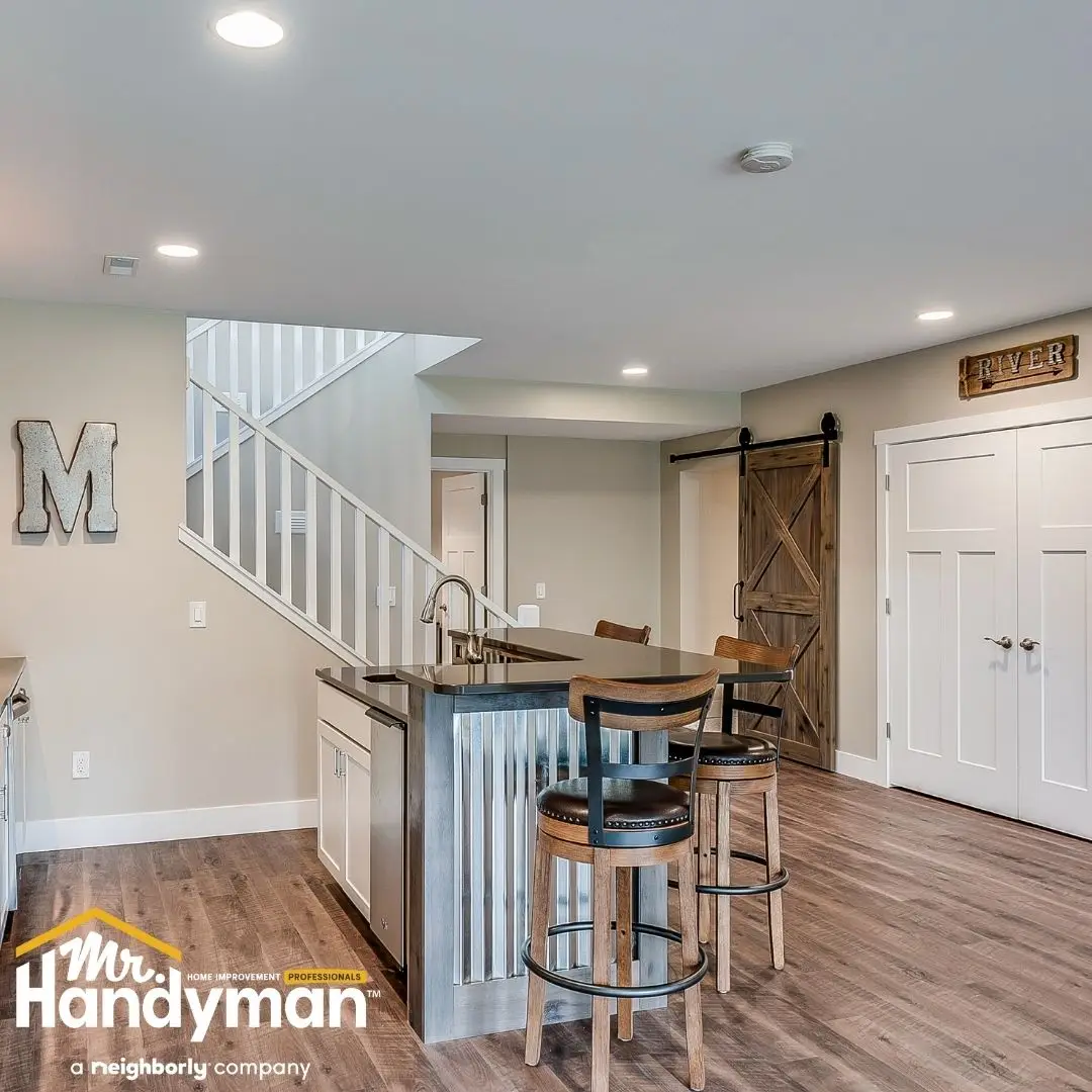Newly renovated basement with modern kitchenette, island seating, and barn door installed by Mr. Handyman of Bethlehem and Allentown