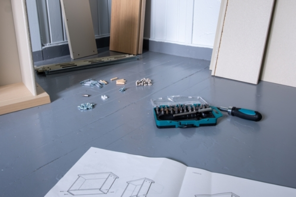 IKEA installation service with unpacked parts and instruction manual laid out.
