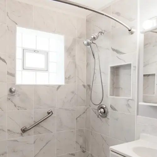 A grab bar in a shower with marble tile