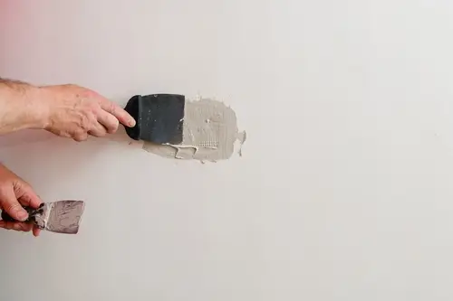 Handyman patching drywall cracks and holes inside a home