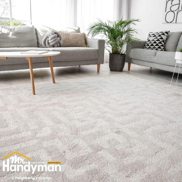 A modern living room showcasing a grey couch and a clean white rug on the floor.