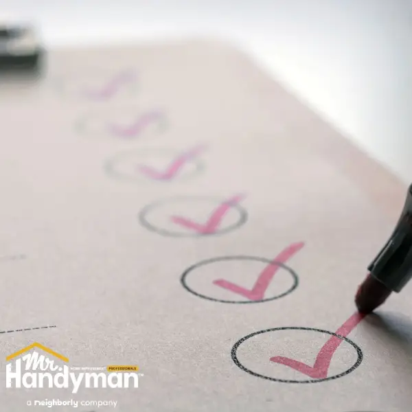 A close-up of a pen marking a pink check mark inside a circle on a checklist.