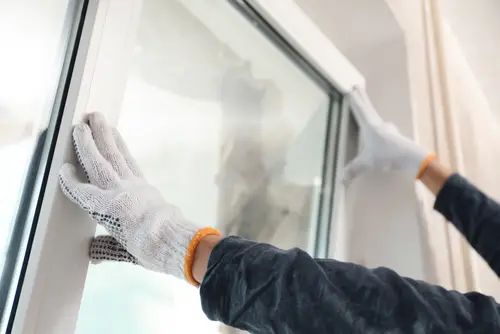 Professional installer replacing a vinyl window indoors