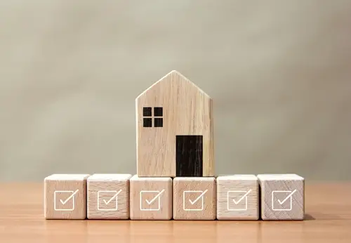 Wooden block house sitting on smaller blocks with check marks