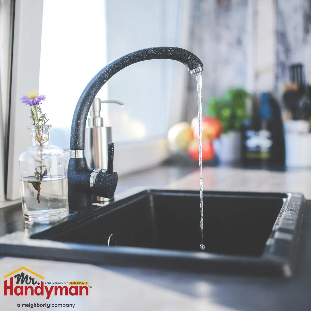 A modern kitchen sink with a tall-curved faucet running water.