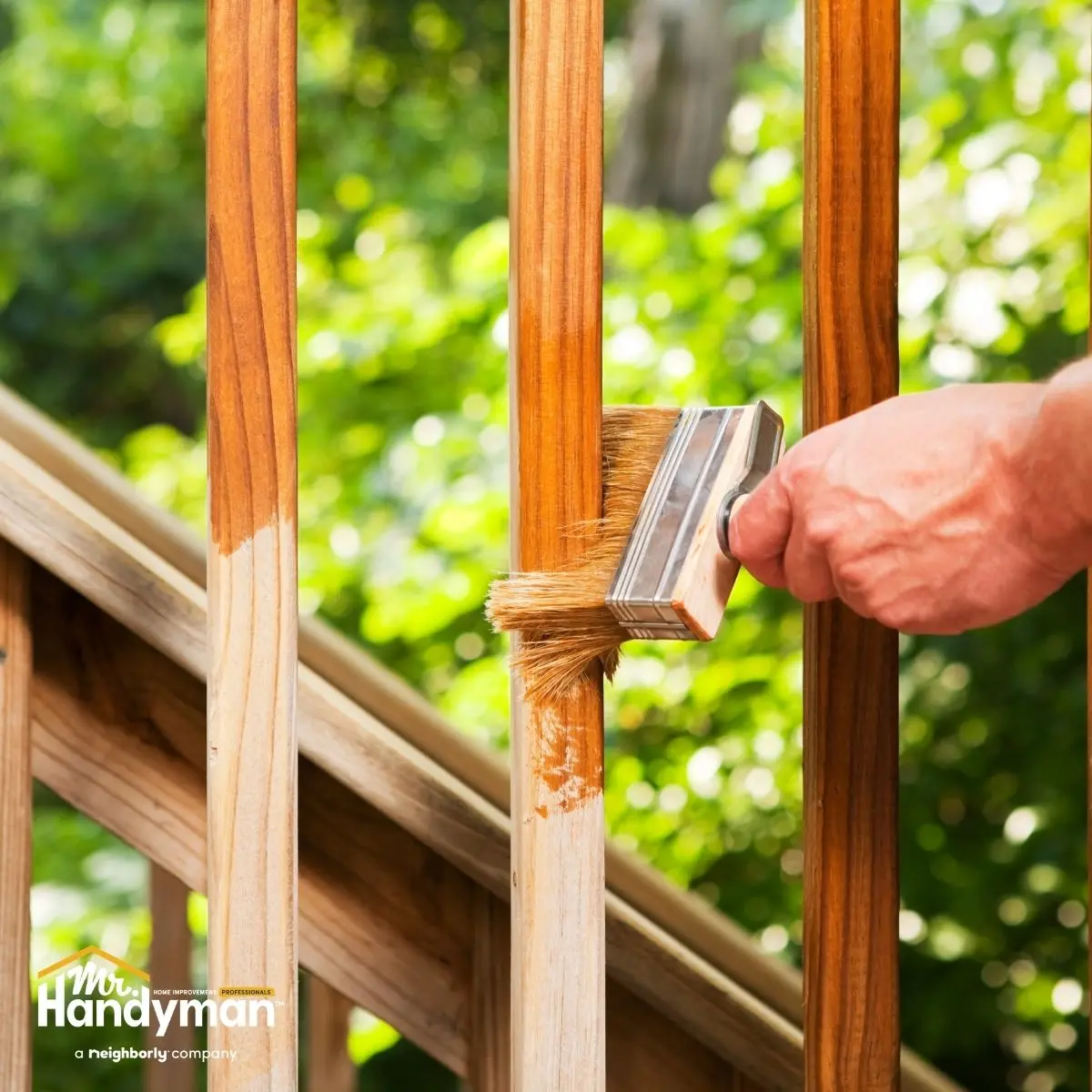 a person&rsquo;s hand is painting a wooden railing