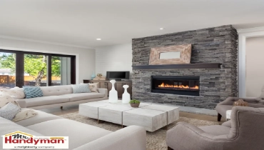 A cozy living room features a modern stone fireplace with a lit fire.