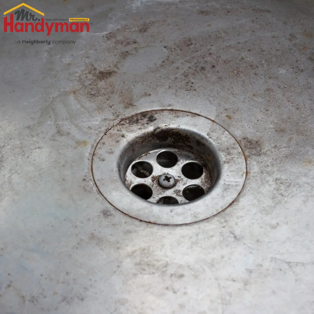 close-up of a dirty-stained metal sink drain with rust and grime buildup
