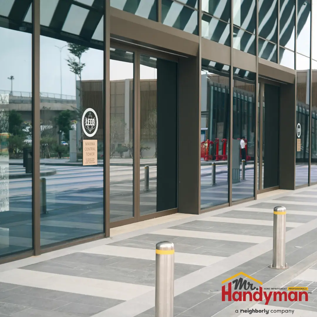 The entrance of a building featuring sleek glass and metal sliding doors with reflective surfaces.