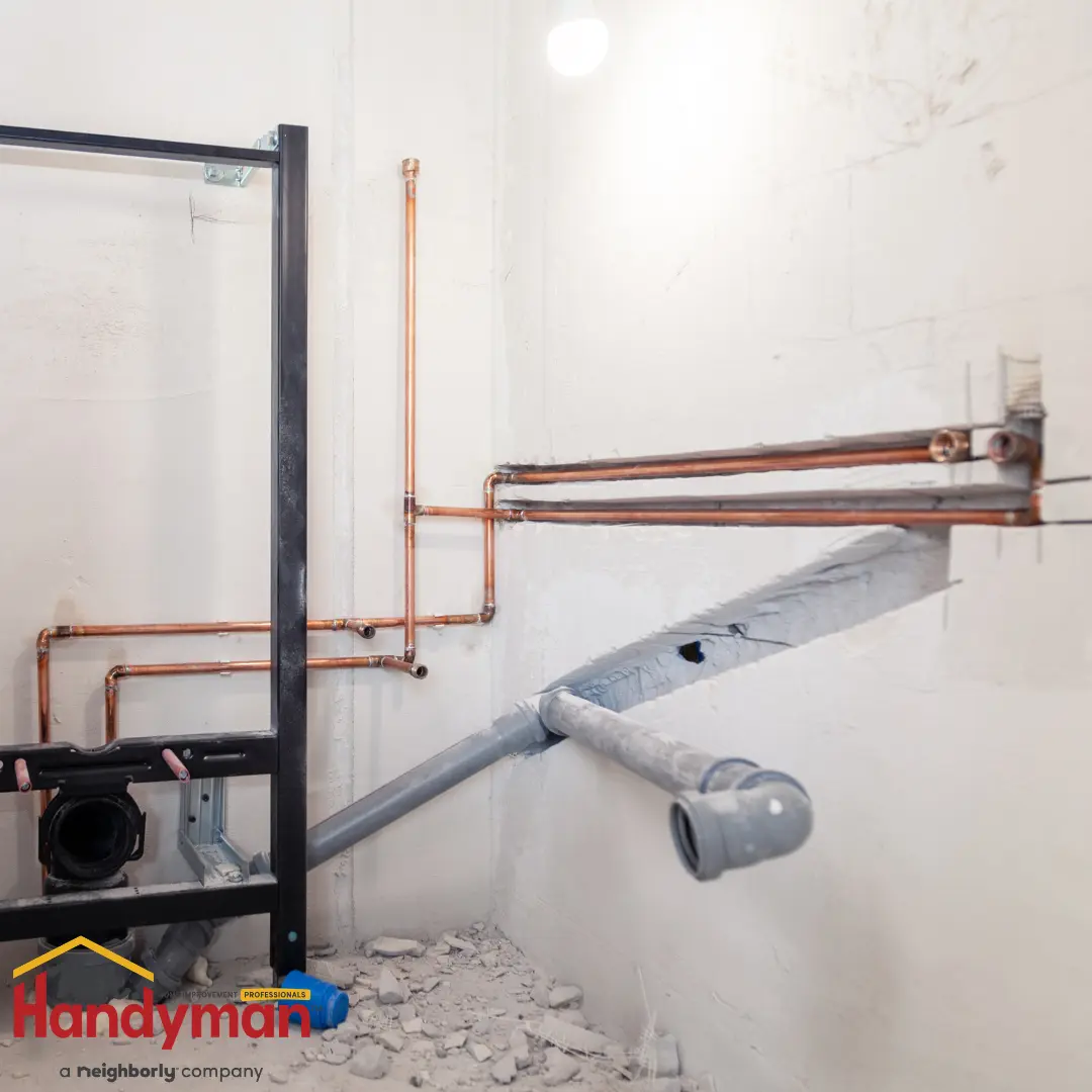 Copper and gray plumbing pipes installed on a white wall.