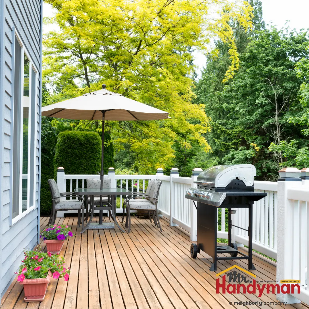 A backyard patio with a wooden deck and a grill.
