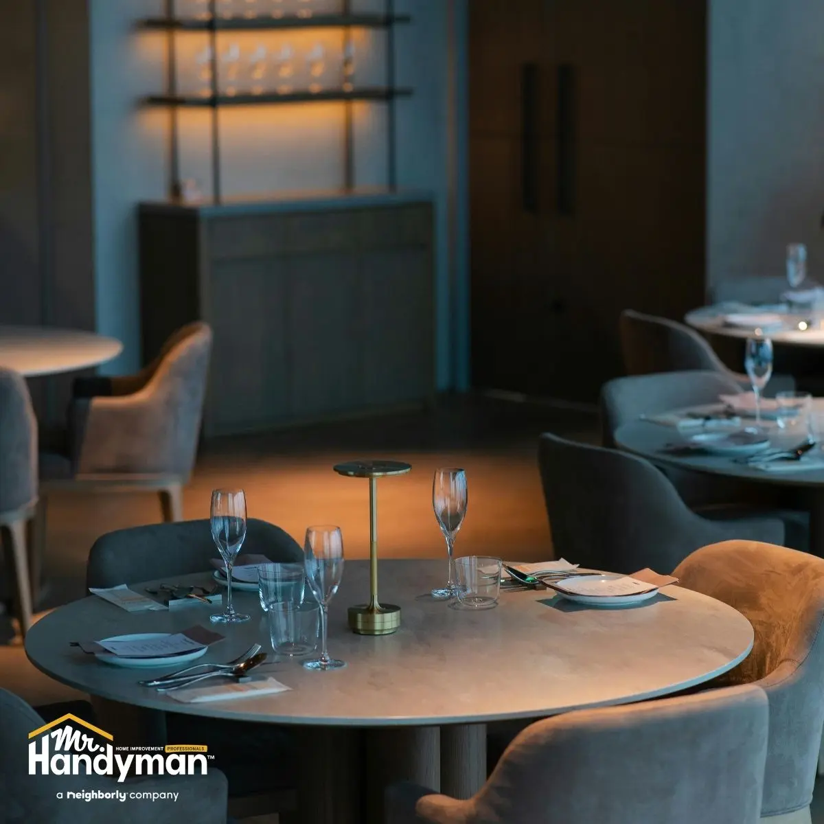 Dining tables set with glassware and napkins in a softly lit.