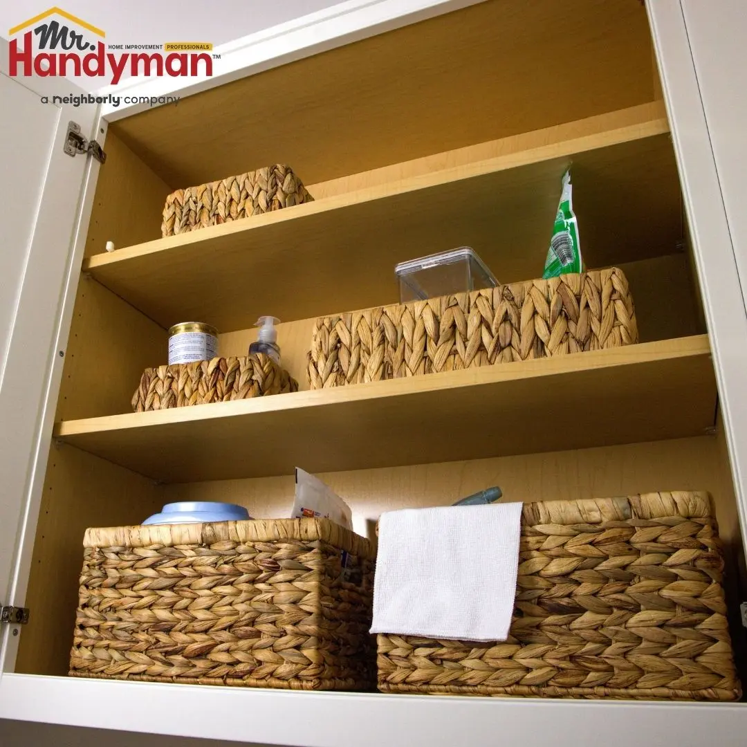 Open wooden kitchen cabinet shelves organized with woven wicker baskets.