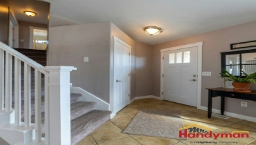 Bright and inviting entryway featuring a staircase, door, and decorative table.