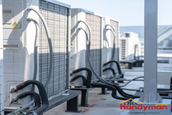 A row of rooftop air conditioning units with visible condenser coils and refrigerant lines.