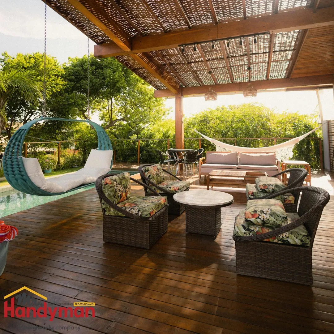 A cozy outdoor terrace with a pergola roof, featuring wicker furniture, a hanging swing, and a hammock overlooking a lush garden.
