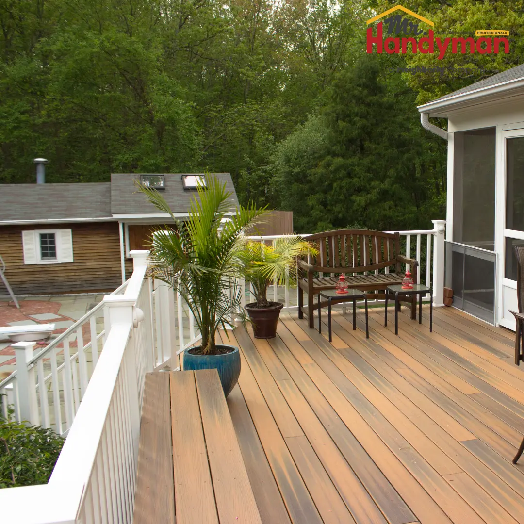 spacious wooden deck with potted plants-surrounded by green trees and a neighboring house