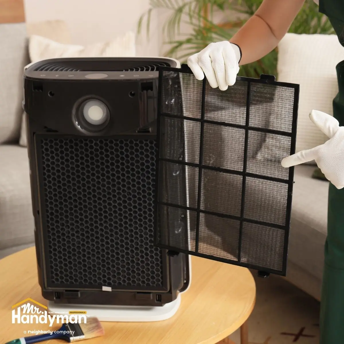 Person removing a dirty filter from a home air purifier.