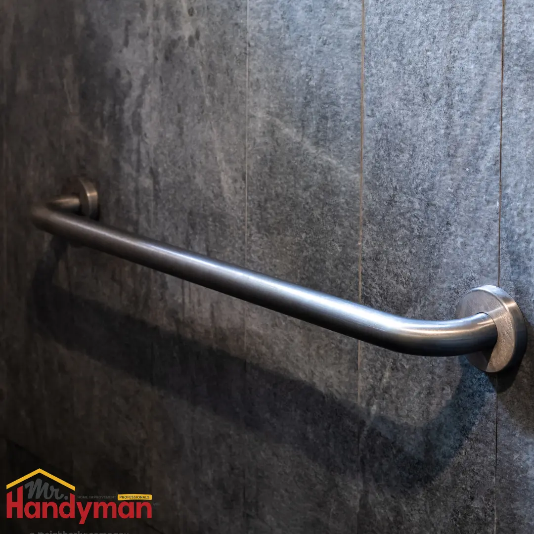 stainless steel grab bar mounted on a dark textured wall.