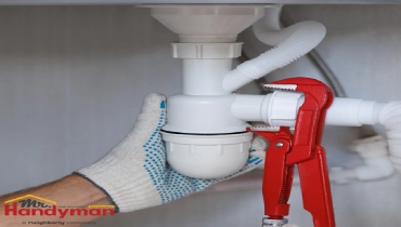 Mr. Handyman technician repairing a leaking faucet and inspecting supply lines.