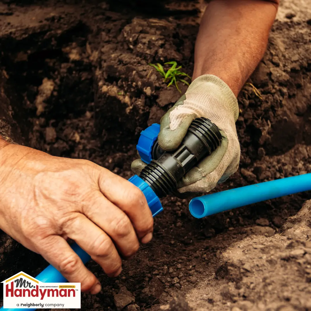 Hands connecting a blue irrigation pipe with a black fitting.