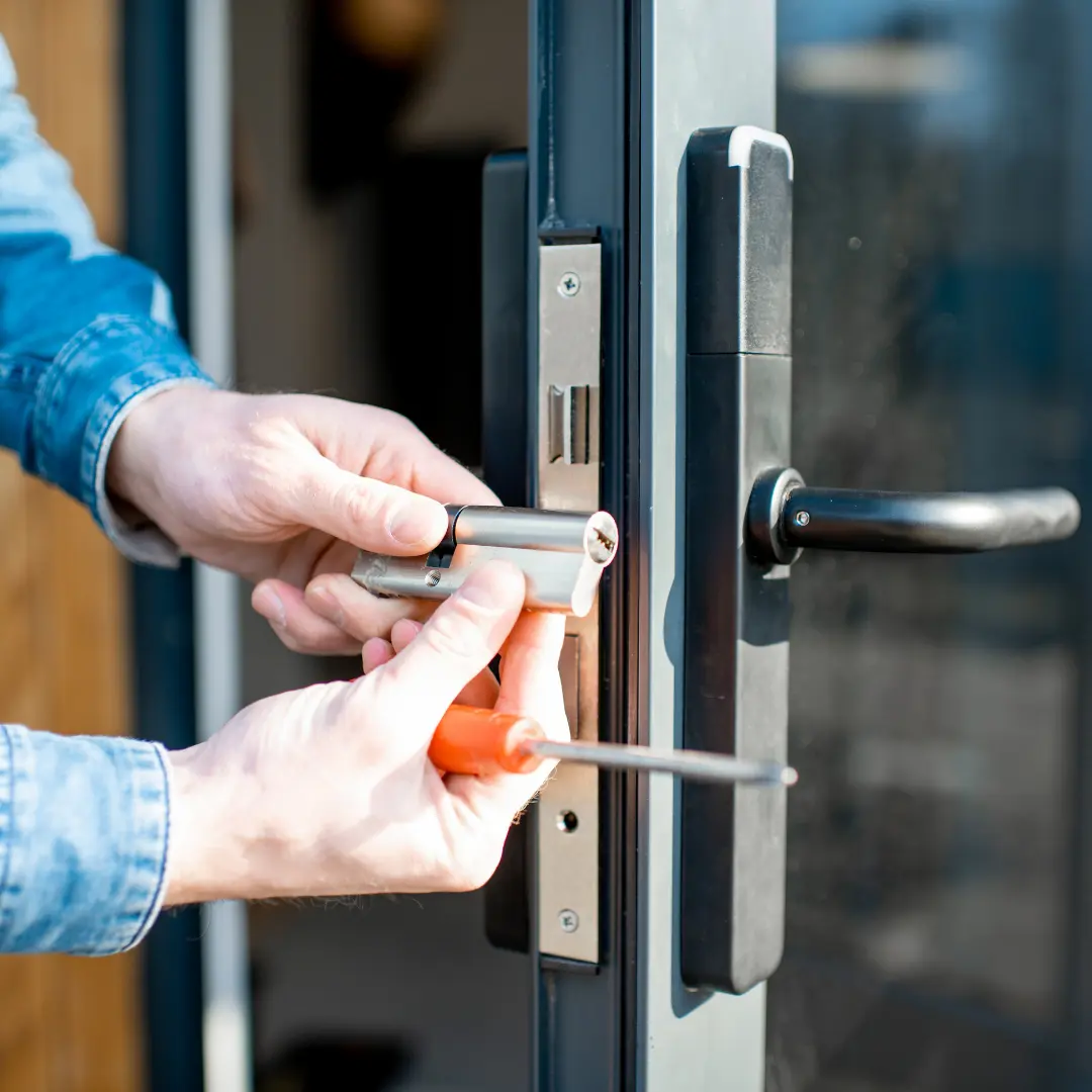 A person replacing a door lock using a screwdriver.