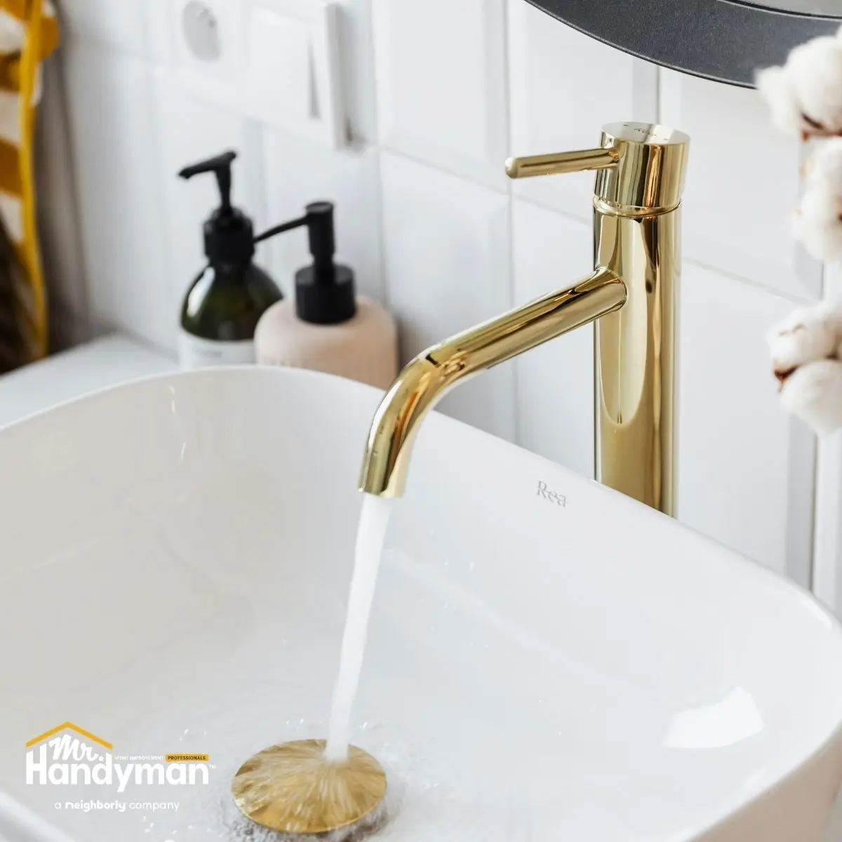 Elegant bathroom scene featuring a polished gold faucet flowing water into a white sink.