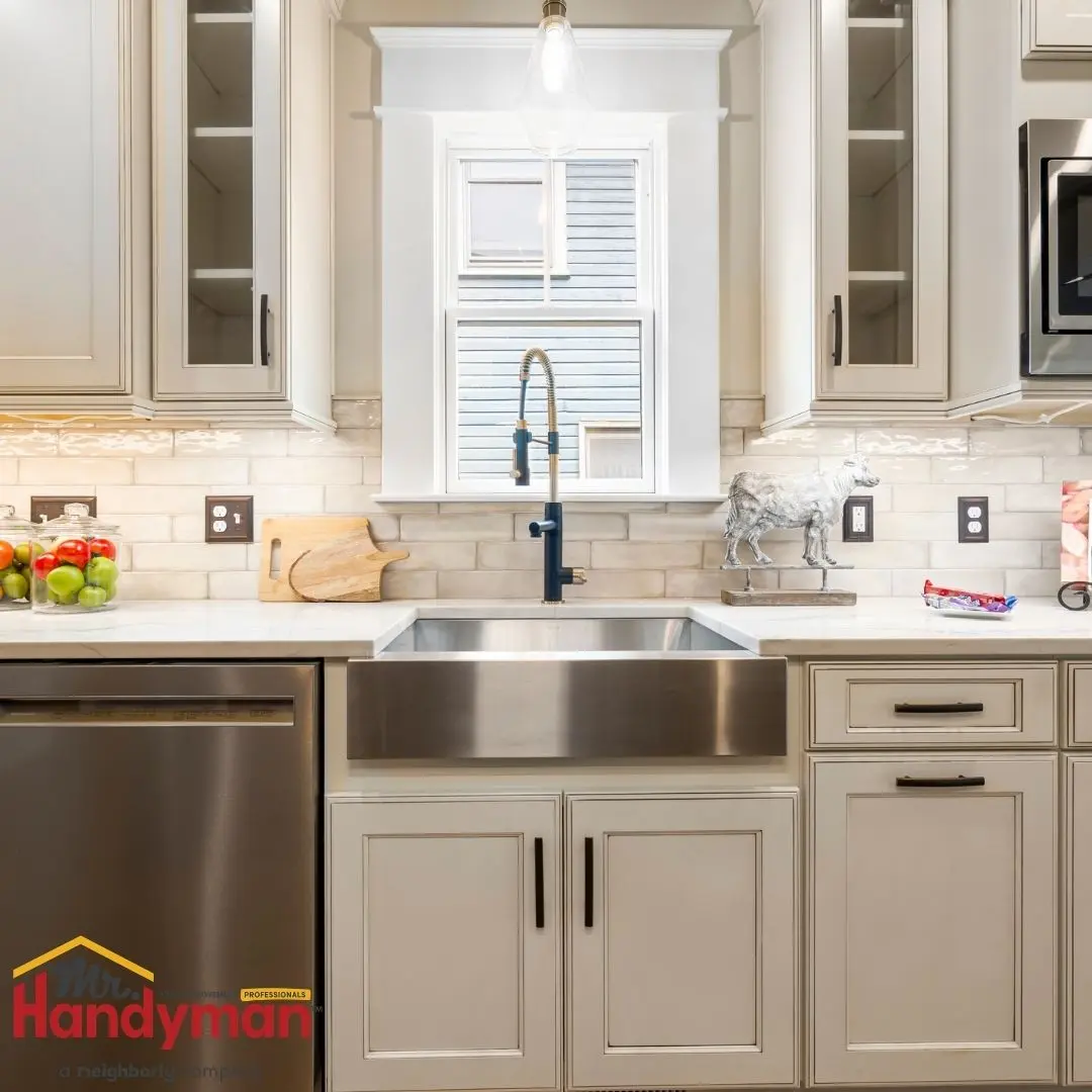 Handyman inspecting kitchen plumbing under a sink before a summer hosting event in Murfreesboro Tennessee.