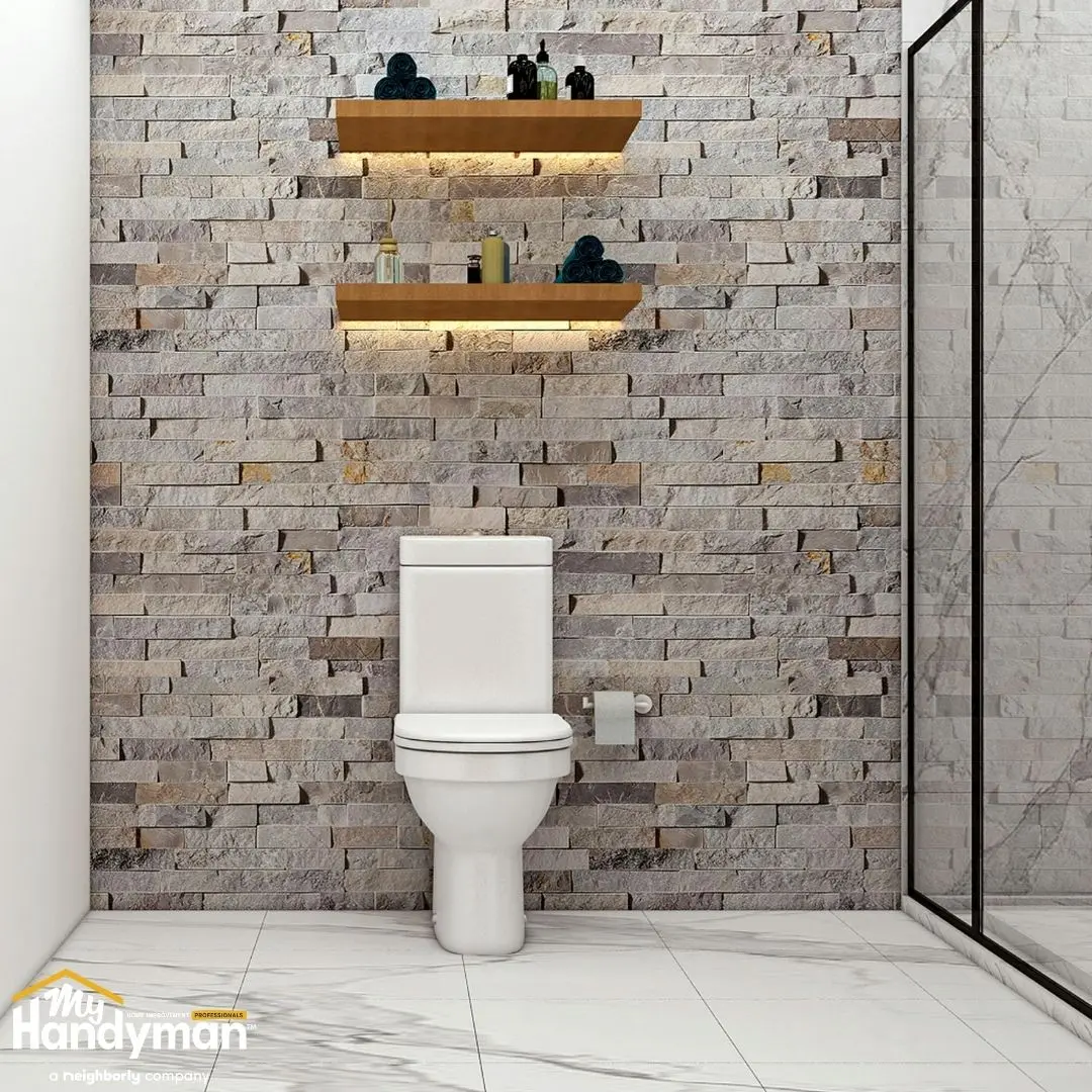 Modern bathroom featuring a white toilet against a textured stone wall.