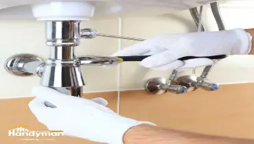 Handyman inspecting outdoor faucet and plumbing in South Oklahoma City OK home.