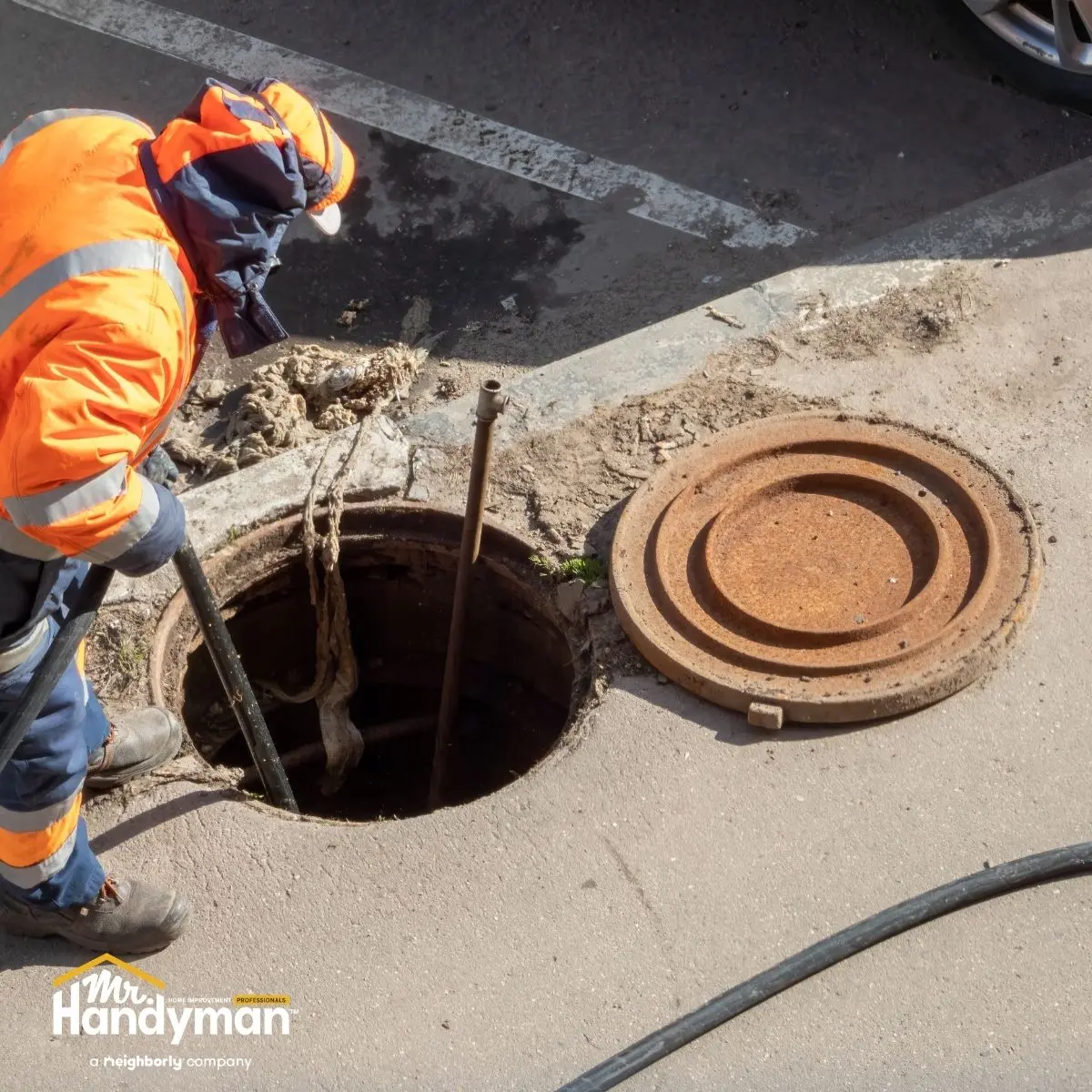 A worker inspects large man hole.