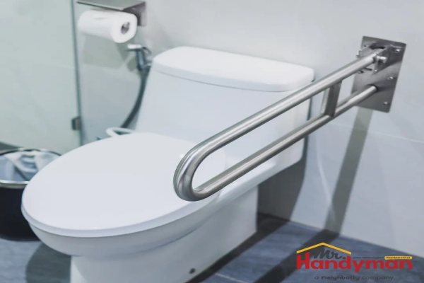 A stainless steel U-shaped grab bar mounted beside a white toilet in a modern bathroom.