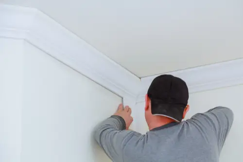 Man installing DIY crown molding.