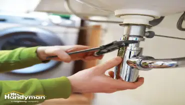 Handyman inspecting under-sink plumbing in a Murfreesboro Tennessee home during spring maintenance
