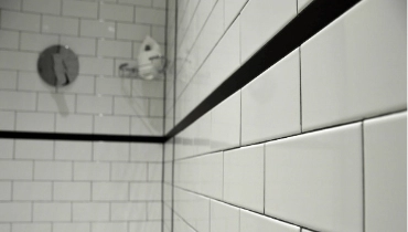 A newly completed residential shower remodel with white tile and black trim