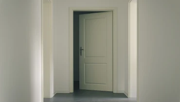 White wall showcasing ajar white panelled door.