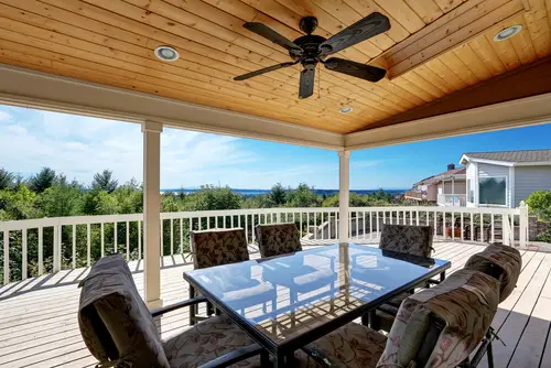 Backyard deck with a flat roof and outdoor furniture under cover.