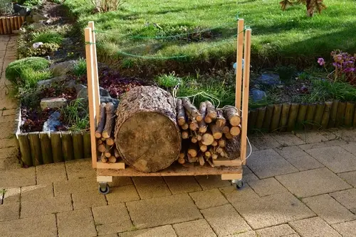 Mobile handmade firewood cart on wheels fully stocked with chopped wood