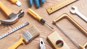 A collection of tools laid out for a handyman to use while completing a fall maintenance checklist.