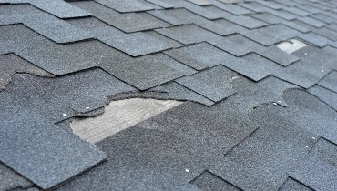 A residential roof with a section of damaged shingles that require roof repair services.