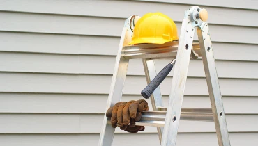 A ladder with a hard hat and gloves.