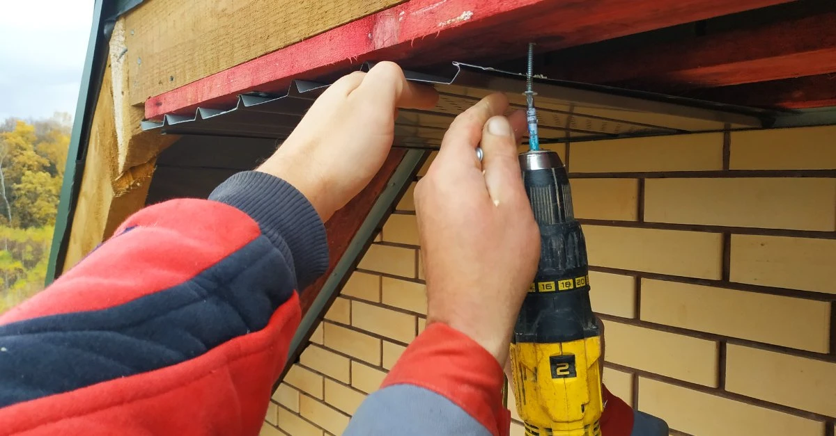 Two handymen providing trim repair services that involve replacing the soffit on a home&rsquo;s roofline.