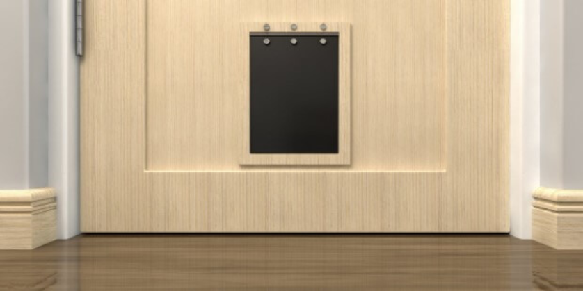 An interior view of a black flap installed as a pet door at the bottom of a door in a residential entryway.