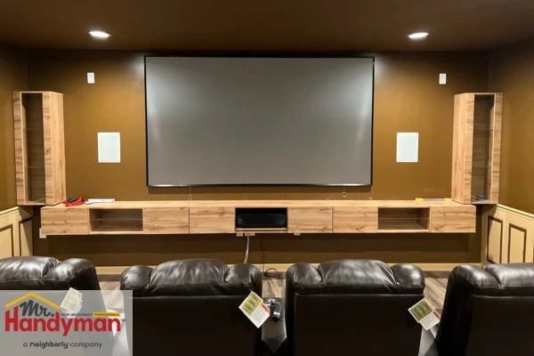 Home theater setup in finished basement with seating and screen installed by Mr. Handyman