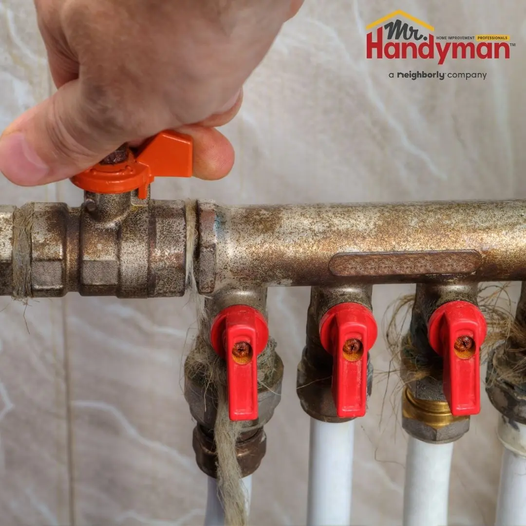 Handyman inspecting a water shutoff valve before summer travel at a home in Murfreesboro Tennessee