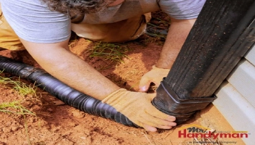 Mr. Handyman technician inspecting exterior caulking and deck condition on a Dallas, Texas home before summer.