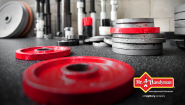 Red and silver gym weights of different sizes on a gym floor.